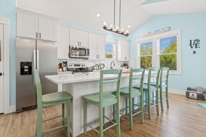 a kitchen with white cabinets and green bar stools at Salty Kisses - Let The Beach Reconnect Your Souls in Corolla