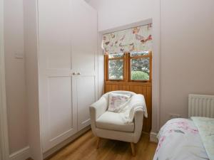 a bedroom with a white chair and a window at The Pheasant One in Usk