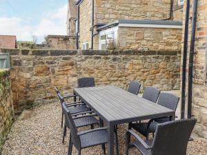 a table and chairs on a patio with a stone wall at Fairhaven in Alnmouth