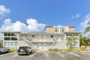 Un edificio con coches aparcados en un estacionamiento. en Pompano Jumbo - Sleeps 16 & priv pool, en Pompano Beach