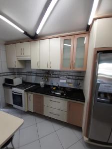 une cuisine avec des armoires blanches et des comptoirs noirs dans l'établissement Apartamento inteiro na Enseada, à Guarujá