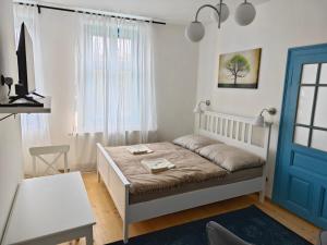 a small bedroom with a bed and a blue door at Penzión Záruby in Smolenice