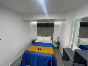 Dormitorio pequeño con cama amarilla y azul en Hotel GALENO en Veracruz