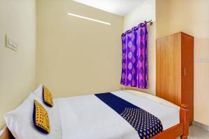 een slaapkamer met een bed en een raam met paarse gordijnen bij OYO Hotel Sri Thirumala Lodge in Bangalore