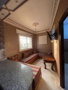 a room with a bed and a couch and a window at Appartement el hichou 1 in Ksar es Sghir