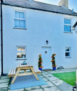 uma casa azul com uma mesa de piquenique em frente em White Horses Anglesey em Newborough