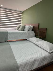 2 Einzelbetten in einem Zimmer mit Fenster in der Unterkunft Casa Niza in Bogotá