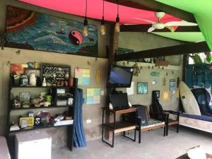 Habitación con escritorio y tabla de surf en la pared. en Farah Hostel Suítes Camping Smartcamp e Passeio de barco, en Boicucanga