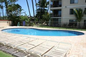 a swimming pool with two lounge chairs in front of a building at KIHEI BEACH, #506^ condo in Kihei