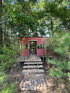 une maison rouge au milieu d'une forêt dans l'établissement The Happy Place In The Trees, à Lake Murray Shores