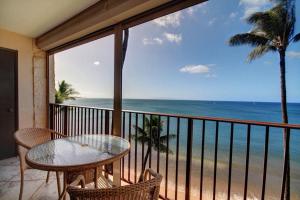 a balcony with a table and chairs and the ocean at KIHEI BEACH, #506^ condo in Kihei