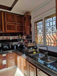 uma cozinha com armários de madeira, um lavatório e uma janela em Apartment Oufella em Tamraght Ouzdar