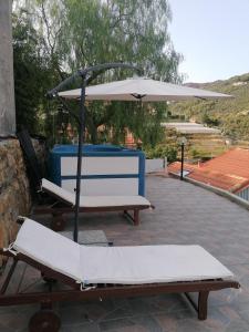 2 ligstoelen en een parasol op een patio bij La casa di Trilly in Sanremo