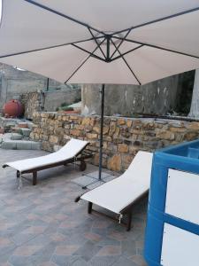 zwei Bänke und ein Regenschirm auf einer Terrasse in der Unterkunft La casa di Trilly in Sanremo
