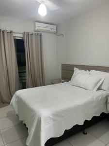 a bedroom with a white bed and a window at Férias na Bahia in Porto Seguro