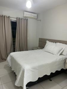 a bedroom with a white bed and a window at Férias na Bahia in Porto Seguro