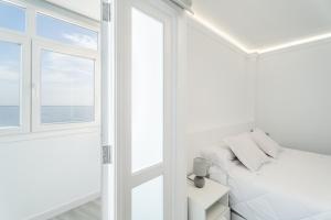 a white bedroom with a bed and a window at Susurros del Mar Sunset in Santa Cruz de Tenerife +22 photos