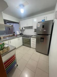 La cuisine est équipée de placards blancs et d'un réfrigérateur en acier inoxydable. dans l'établissement Departamento La Molina, à La Molina