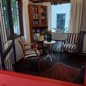 a living room with two chairs and a table at Mulligans Guest Lodge in Hermanus