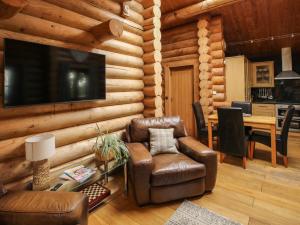 a living room in a log cabin with a television and a table at Brynallt Country Park in Ellesmere