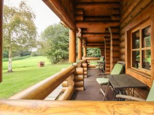 a porch of a log cabin with a table and chairs at Brynallt Country Park in Ellesmere