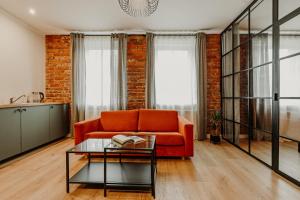 a living room with an orange couch and a table at Old brick boutique apartments in Klaipėda