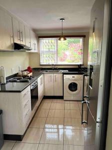 a kitchen with white cabinets and a washer and dryer at Luba Suite in Durban