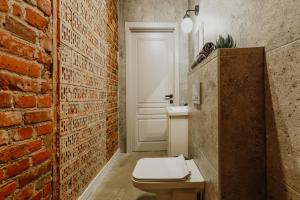 a bathroom with a white toilet and a brick wall at Old brick boutique apartments in Klaipėda