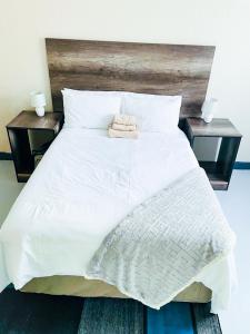 uma grande cama branca com duas mesas de cabeceira e duas mesas em JBC Guest House em Bushbuckridge