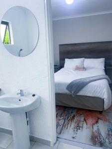 uma casa de banho com uma cama, um lavatório e um espelho. em JBC Guest House em Bushbuckridge