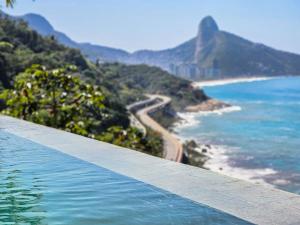 a swimming pool with a view of a beach and the ocean at Linda casa no Joá, com vista incrível do mar do Rio in Rio de Janeiro