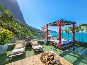 a resort with a pool and a bed and a table at Linda casa no Joá, com vista incrível do mar do Rio in Rio de Janeiro