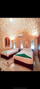 two beds in a room with a stone wall at Al Burj Hotel in Tunis