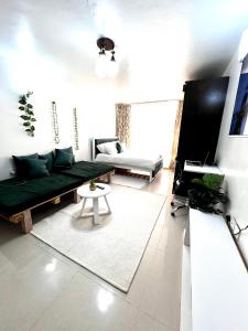 uma sala de estar com um sofá verde e uma mesa em Emerald BnB em Ruaka