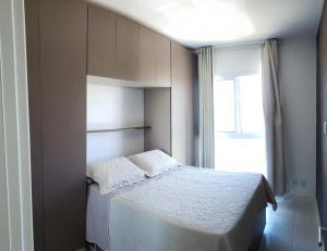ein Schlafzimmer mit einem Bett mit zwei Kissen und einem Fenster in der Unterkunft Apartamento moderno, equipado e confortável in Porto De Galinhas + 48 Fotos