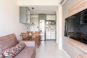 ein Wohnzimmer und eine Küche mit einem Sofa und Stühlen in der Unterkunft Apartamento moderno, equipado e confortável in Porto De Galinhas