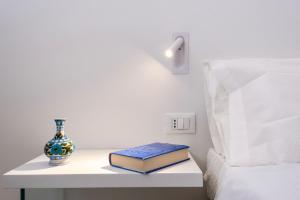 two books and a vase on a table next to a bed at Casa Duca - Marina di Ragusa in Marina di Ragusa