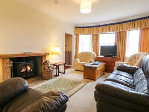 sala de estar con sofá y chimenea en North Lodge, en Forfar