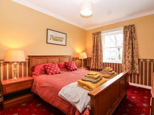 a bedroom with a bed with red sheets and a window at North Lodge in Forfar