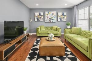 a living room with green couches and a tv at Cozy 4BR Townhome, Family Community, 40 Mins to DC in Sterling