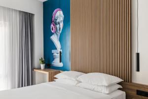 una camera con un letto e un dipinto di una donna con un telefono di The Q Hotel ad Atene