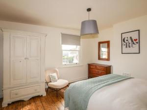 a bedroom with a bed and a chair and a window at Shamrock Cottage in Conwy