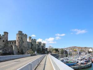 a bridge leading to a castle with boats in the water at Shamrock Cottage in Conwy