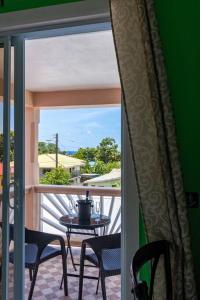 a balcony with a table and chairs and a window at Maggie's Inn in Soufrière