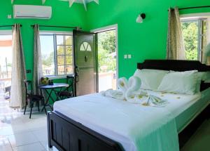 una camera verde con un grande letto con lenzuola bianche di Maggie's Inn a Soufriere