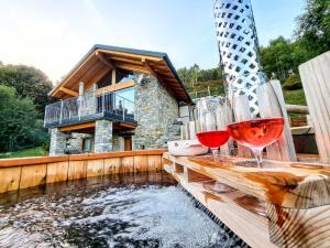 two glasses of wine sitting on a wooden table next to a pond at casa vacanze Ca'del Miro Montemezzo in Bugiallo