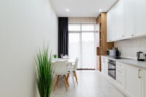 een keuken met witte kasten en een tafel en stoelen bij Luxury Apartments “Dream City” in Oezjhorod