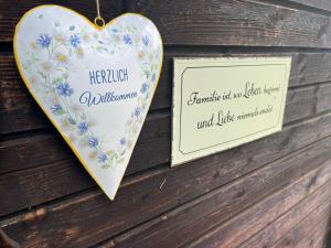 a heart shaped sign hanging on a wall with flowers at Neuwirth Hütte in Gnesau