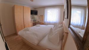 a bedroom with a large white bed and a kitchen at Appartment Brüsl in Strass