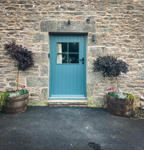 een blauwe deur op een bakstenen gebouw met twee planten bij Tethera, Amma Barn in Shap